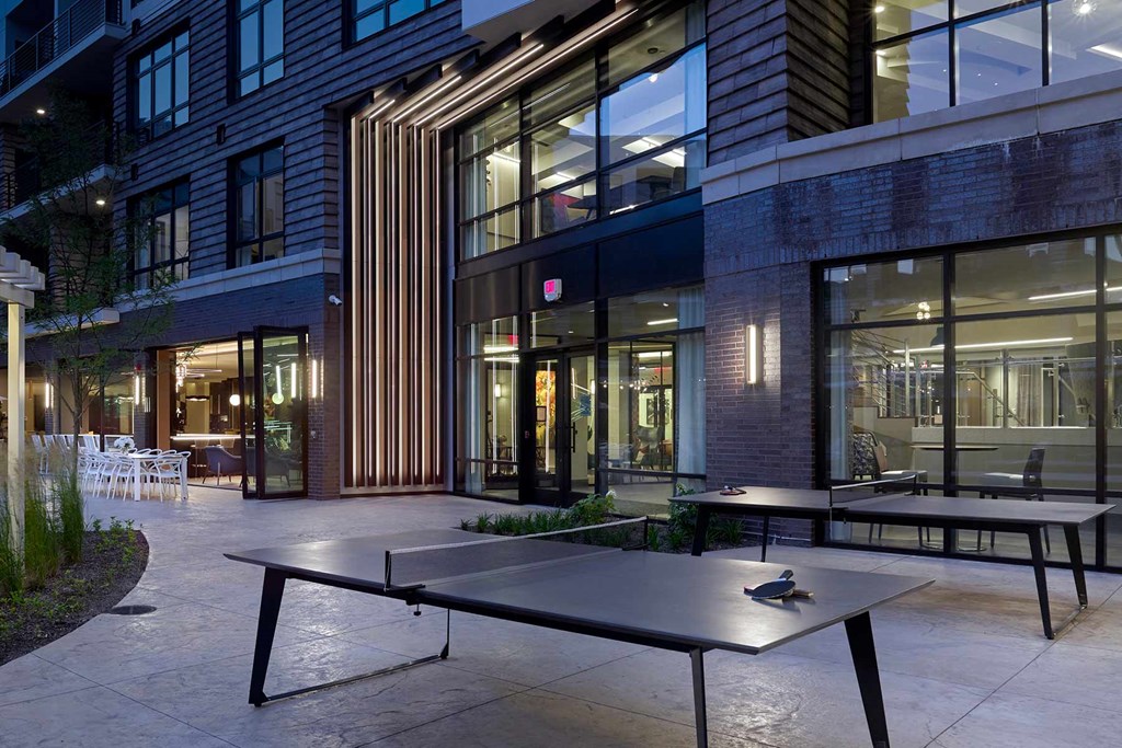 A ping pong table is in the middle of a courtyard.