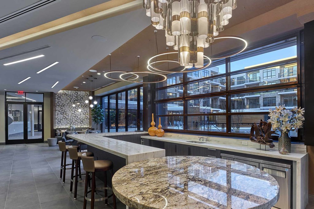 A modern bar area with a marble counter and a large circular chandelier.