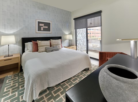Residences A bedroom with a large bed and a grey vase on a table.