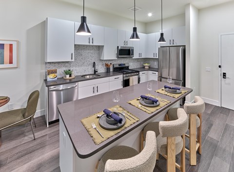 A modern kitchen with a dining table set for two.