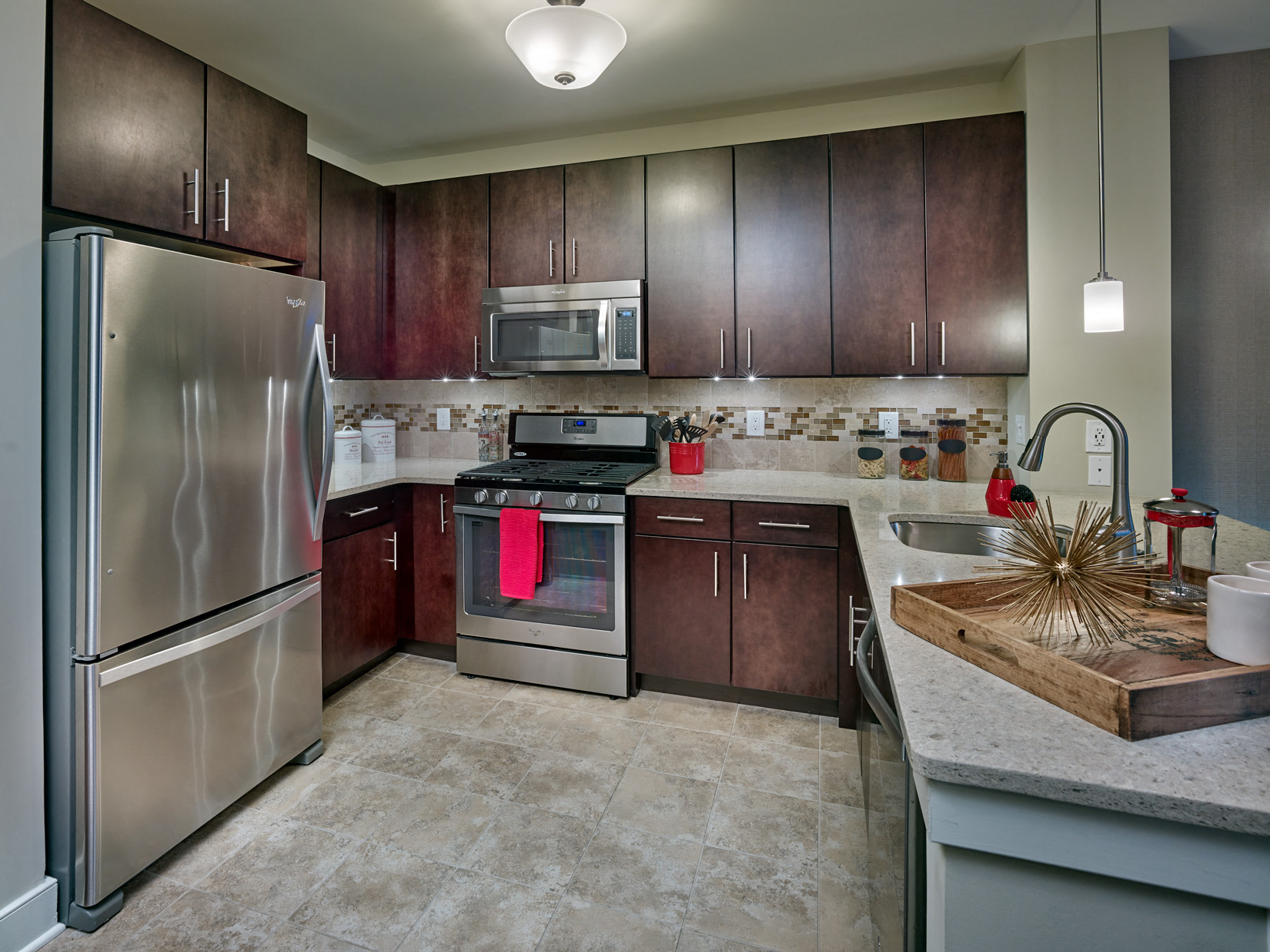 A kitchen with a stainless steel refrigerator and brown cabinets.