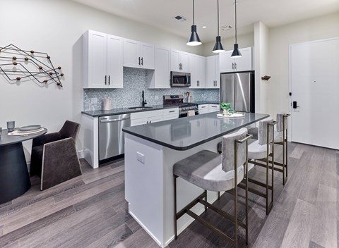 A modern kitchen with a large island and stainless steel appliances.