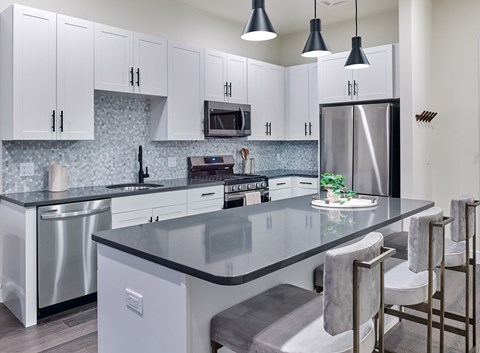 A modern kitchen with a granite countertop and stainless steel appliances.