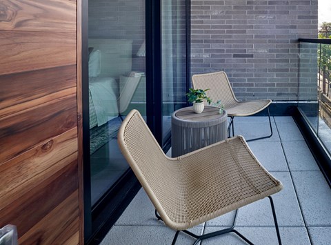 A patio with a chair and a table with a plant on it.