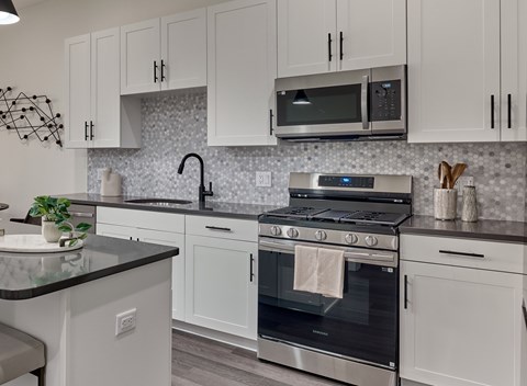 A kitchen with white cabinets and a black countertop.