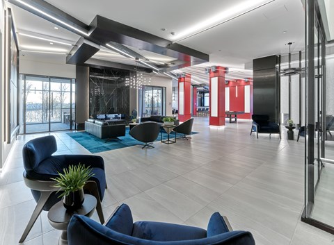 A modern living room with blue chairs and a glass wall.