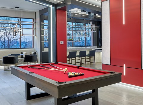 A pool table with a red cloth and a white cue ball and rack.