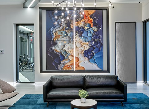 A modern living room with a large abstract painting on the wall.