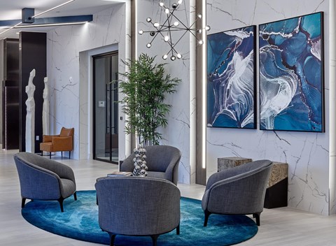 A living room with grey armchairs and a blue rug.