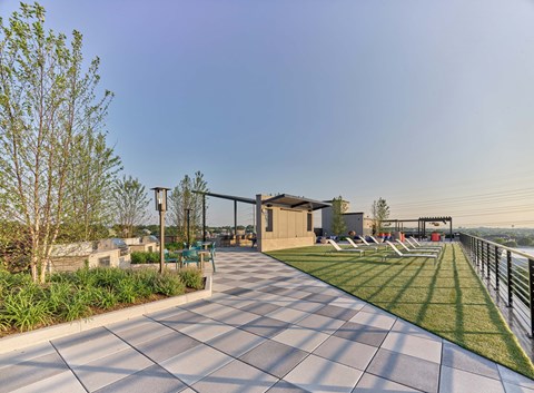 A modern outdoor seating area with a long row of chairs and a building in the background.