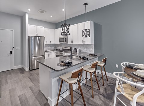 a kitchen with a large island with bar stools and a stainless steel refrigerator