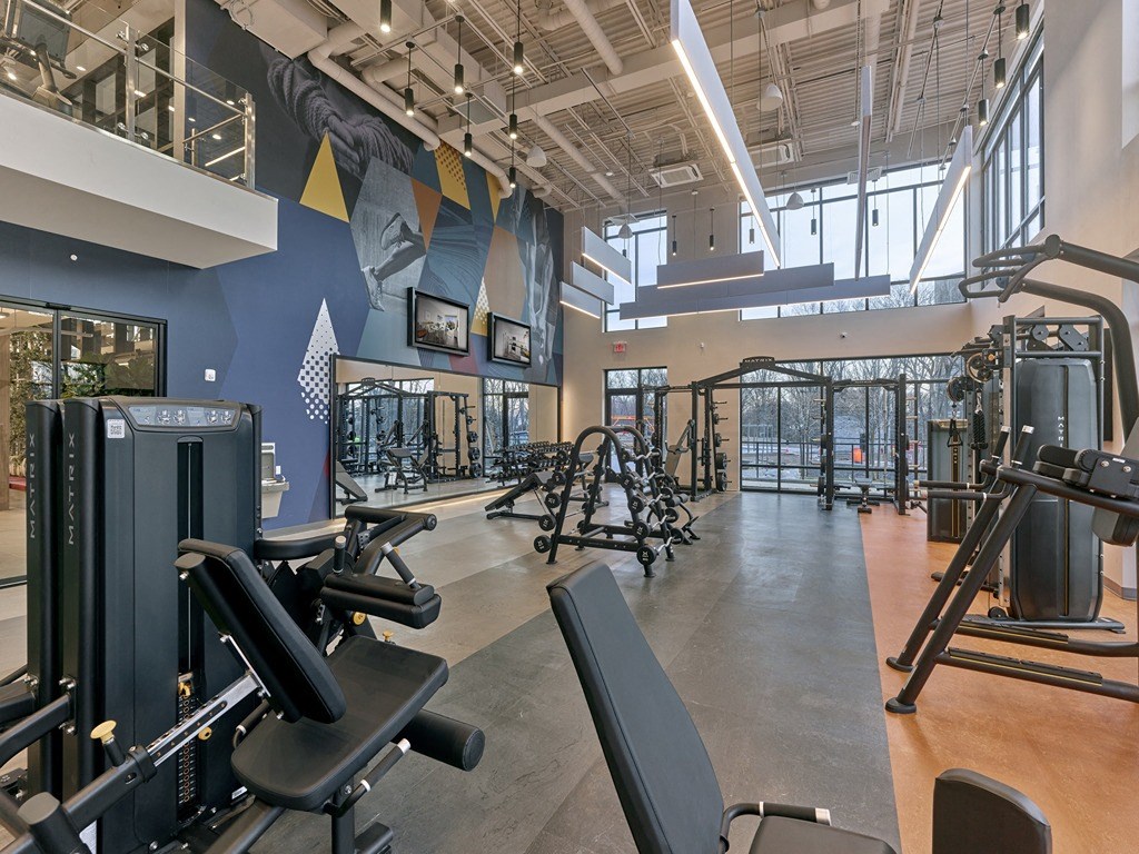 a gym with weights and other exercise equipment in a building with windows