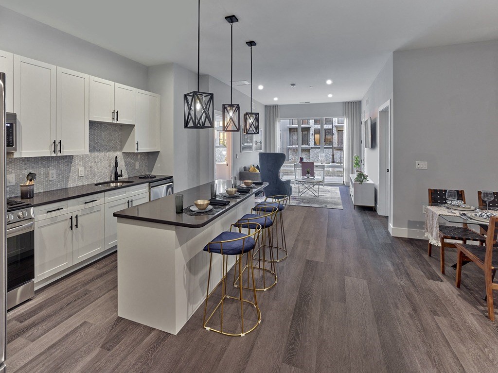 a kitchen with an island and stools in front of a dining room