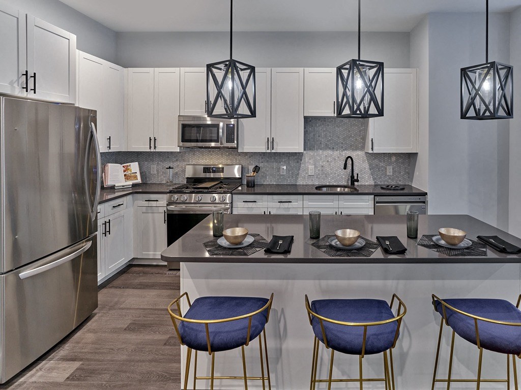 a kitchen with stainless steel appliances and an island with blue chairs