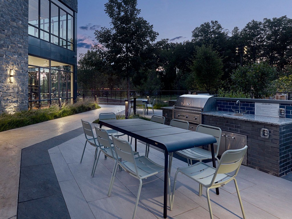 a patio with a table and chairs and an outdoor grill