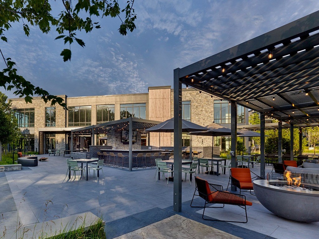 a patio with tables and chairs and a fire pit