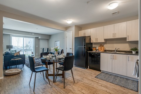 A kitchen with a black refrigerator and wooden floors.