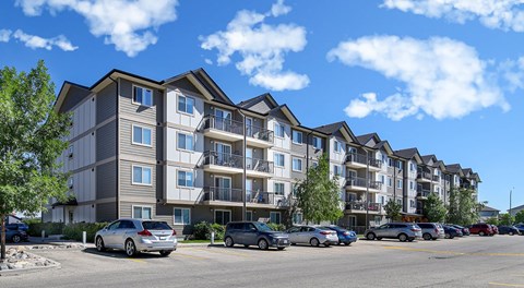 A large apartment building with parking lot in front