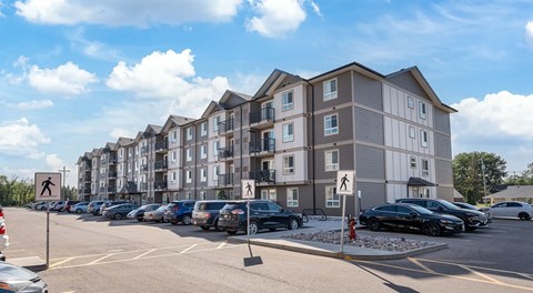 An apartment building with parking lot in front