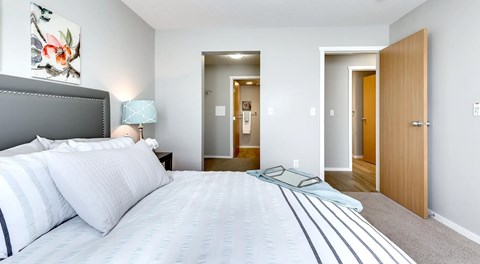 A bedroom with queen sized bed with a walk in closet leading to a ensuite bathroom