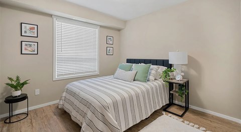 A bedroom with a bed, small nightstand and large window