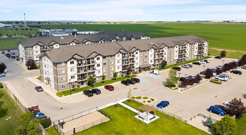 A large apartment building with a large parking lot in front.