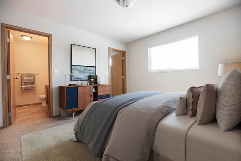 A bedroom with a bed, nightstand, and a window.