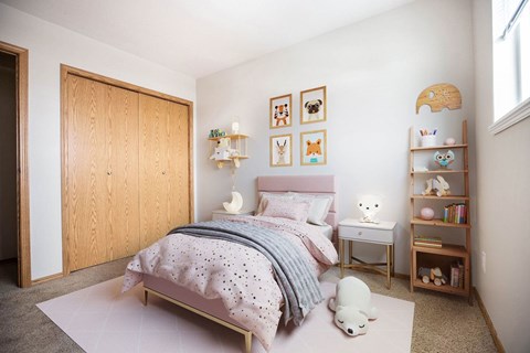 A bedroom with a bed, a nightstand, a bookshelf, and pictures on the wall.