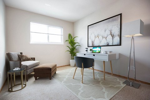 A room with a couch, a chair, a desk, and a potted plant.