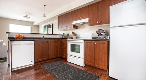 A kitchen with white appliances and wooden cabinets.