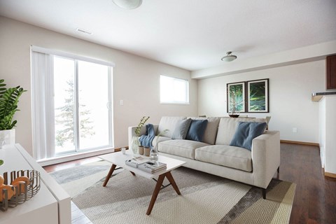 A living room with a couch, a coffee table, and a potted plant.