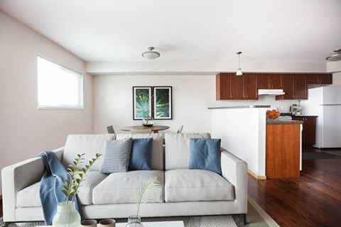 A living room with a grey couch and a painting on the wall.