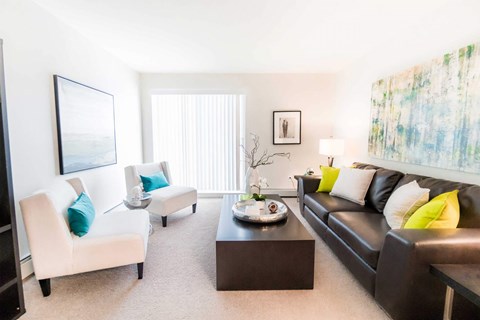 A living room with a black couch, a white chair, and a coffee table.