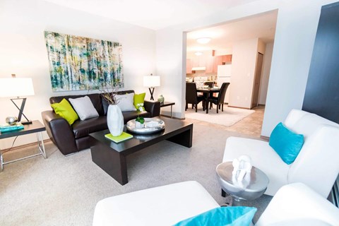 A modern living room with a black and white sofa, a black coffee table, and a white armchair.