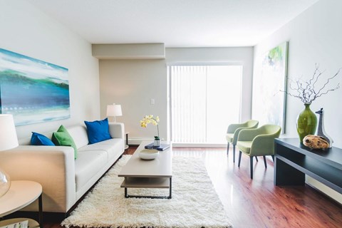 A living room with a white couch, a coffee table, and a painting on the wall.