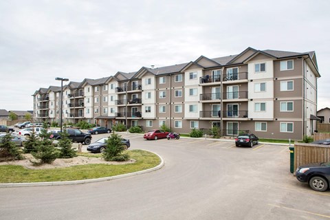 A parking lot in front of a large apartment building.