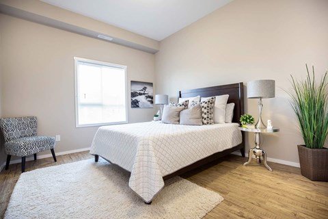A bedroom with a large bed and a chair.