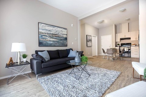 A living room with a grey couch, a coffee table, and a painting on the wall.