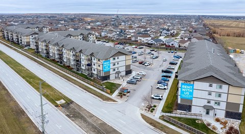 A large apartment complex with a large parking lot behind