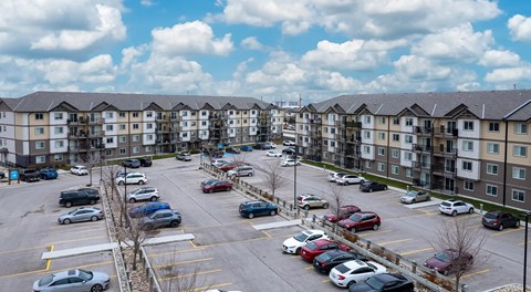 A large apartment complex with a large parking lot in front