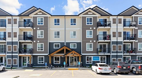 A large apartment building with a parking lot in front.