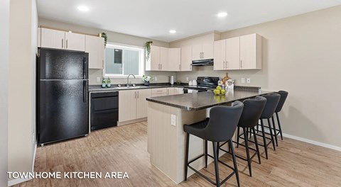 A townhome u shaped kitchen with light cabinets and black appliances. Eating bar with four chairs