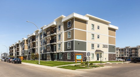 Large multi level apartment building with parking along the street and private parking lot behind