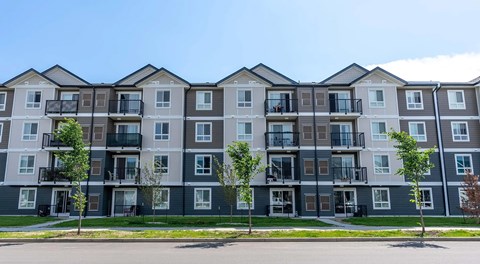 A four storey tall apartment building with a roadway in front