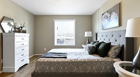 A bedroom with a bed, dresser, and window.