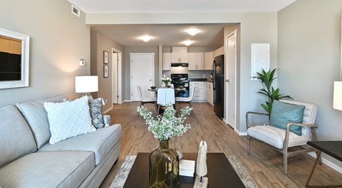 A living room with a couch, coffee table and chair, next to an open kitchen