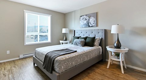 A  bedroom with a large bed, two nights stands and a big window