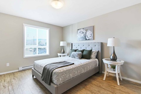 A bedroom with a large bed and a window overlooking a cityscape.