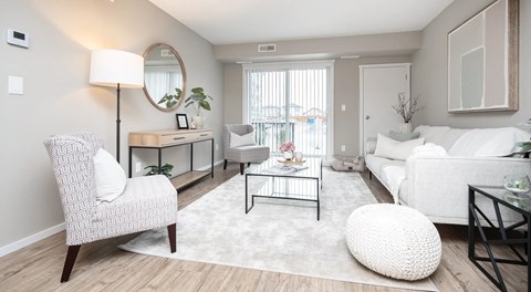 A modern living room with a white sofa, chairs, coffee table and a large glass sliding balcony door
