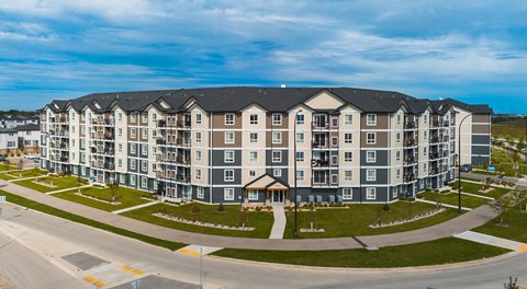 A large five story apartment complex with parking in behind